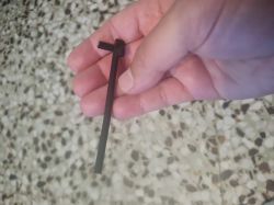 Black plastic cable tie held in a hand against terrazzo-style floor background