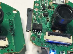 Close-up of a camera circuit board with visible lens, T25S80 flash memory chip, and connectors.
