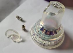 Close-up of a damaged GU10 reflector with glass shard and mounting pins.
