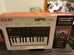 Pudełko z kontrolerem MIDI Akai Professional MPK Mini na półce w magazynie.