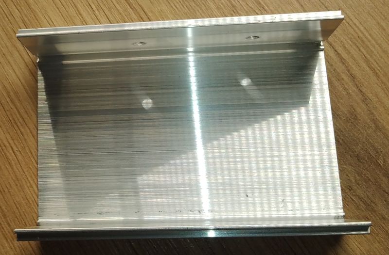 Aluminiowy profil obudowy lub radiatora leżący na drewnianym blacie