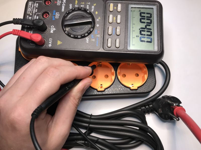 Measuring power strip grounding using a Brymen multimeter.