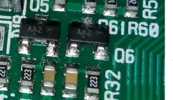 Dwa czarne elementy SMD oznaczone AA2 w obudowie SOT-23 na płytce PCB