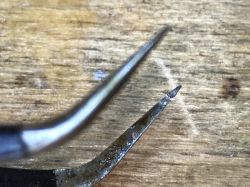 Sharp tip of a soldering tool on a wooden background