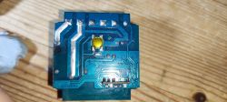 Electronic circuit board with a yellow button on a wooden background.