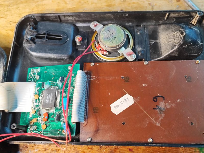 Wnętrze telefonu stacjonarnego z lat 90., z widocznymi układami scalonymi i głośnikiem.