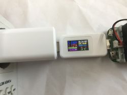 USB tester showing 5.23 V and 1.127 A connected to white power adapter and PCB.