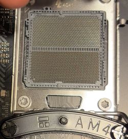 Zbliżenie na socket AM5 z widocznymi delikatnymi zabrudzeniami lub uszkodzeniami w lewym dolnym rogu