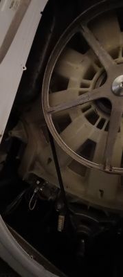 Wnętrze pralko-suszarki Hotpoint Ariston z widocznym bębnem i paskiem napędowym.