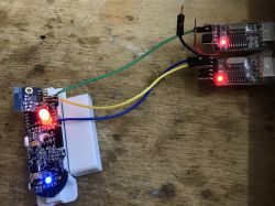 The photo shows a door sensor being tested with connected wires and a lit red LED.