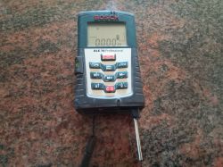 Dalmierz laserowy Bosch DLE 70 Professional na tle brązowego blatu.