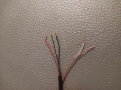 Zdjęcie czterech odsłoniętych przewodów różnego koloru: czerwonego, niebieskiego, czarnego i białego w oplocie.