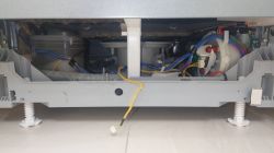 Wnętrze dolnej części zmywarki Bosch z widocznymi przewodami i elementami technicznymi.