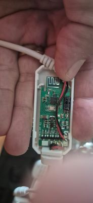 Electronic module circuit board with visible wires and electronic components, held in a hand.
