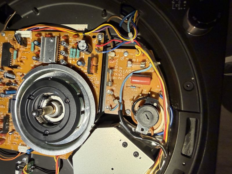Wnętrze urządzenia: płytka PCB z przewodami, bezpiecznikami i metalowym zespołem napędu