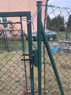 Brama ogrodzeniowa z zamkiem i elektrozaczepem, zamocowana na metalowym słupku.
