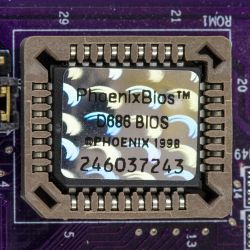 Zbliżenie na dawny chip BIOS PhoenixBios D686 zamocowany na płycie głównej.