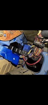 Zbliżenie na przewody i instalację elektryczną w samochodzie, z niebieską skrzynką bezpieczników.