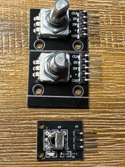 Two KY-040 rotary encoder modules and an IR receiver module on a wooden surface