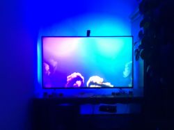 TV with blue and purple LED backlighting mounted on the wall behind it