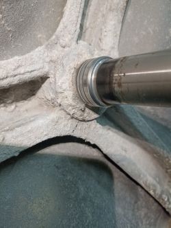 Pewien metalowy przedmiot z widocznym elementem wałka i wokół osiadłej substancji.