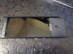 Small glass pane in a black plastic frame on a textured rubber work mat