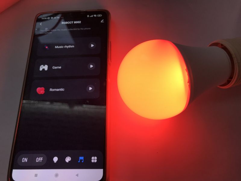 Pairing RGB/CCT LED Bulb with Tuya App RGB/CCT LED bulb glowing red next to a smartphone with the Tuya app.