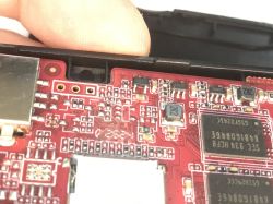 Close-up of a red PCB with SMD components and a shielded module, partially inside a casing