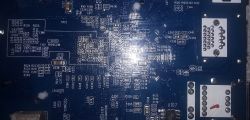 Zdjęcie płytki drukowanej z widocznymi ścieżkami i elementami elektronicznymi, oświetlone błyskiem lampy.