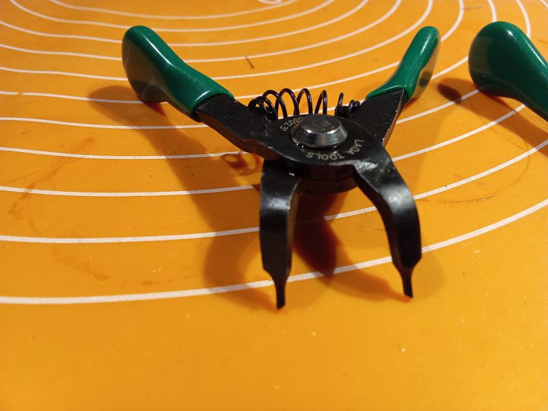 Szczypce do pierścieni Segera na pomarańczowej macie.