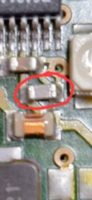 Zbliżenie na płytkę PCB, z zaznaczonym czerwonym kółkiem elementem.