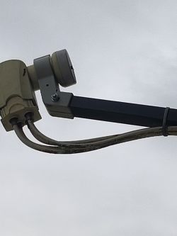 Zbliżenie na konwerter satelitarny (LNB) z czterema podłączonymi przewodami koncentrycznymi na wysięgniku anteny.