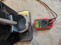 Miernik elektryczny obok ekspresu do kawy Siemens EQ300 pokazujący napięcie 131V.