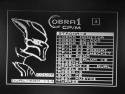 Menu startowe systemu Cobra 1 CP/M wyświetlone na czarno-białym ekranie, z grafiką głowy i listą programów po prawej.