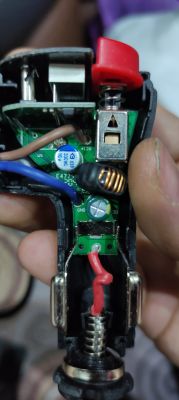 Zbliżenie na rozebrany rozdzielacz gniazda zapalniczki samochodowej z widoczną płytką elektroniczną.