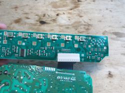 Dwie płytki PCB z programatora zmywarki, połączone taśmą; widoczne przyciski i elementy elektroniczne.