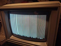 Monitor CRT Commodore 1802 z testowym wzorem pionowych pasów i opisami częstotliwości u dołu ekranu.