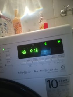 Panel sterujący pralki z wyświetlaczem pokazującym 40 P:13, z butelkami detergentów na górze.