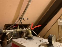 Zbliżenie na instalację hydrauliczną z widocznym kolankiem i przewodem w pomieszczeniu gospodarczym.