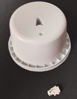 Plastic lid and small white component on a black background.