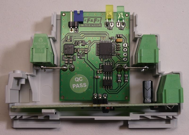 Płytka drukowana urządzenia elektronicznego w obudowie montażowej z zielonymi złączami śrubowymi.