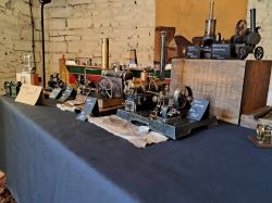 Prezentacja modeli maszyn parowych na stole z oznaczeniami dat.