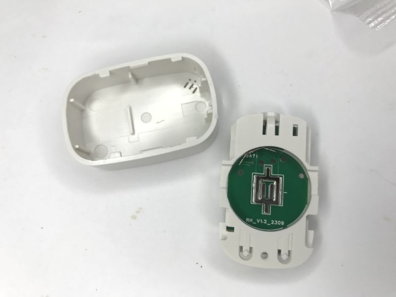 Opened white sensor with cover and green circular PCB featuring a central metal element