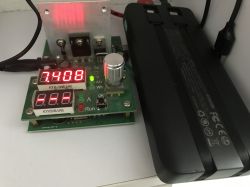 Power bank next to an electronic meter with a red display reading 7.408