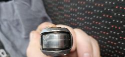 Część mechaniczna z widocznym zużyciem trzymana przez dłoń na tle siatki.