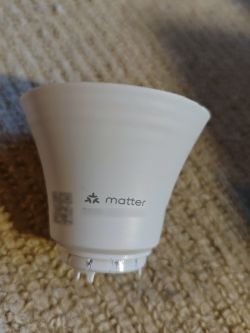 A white light bulb with the Matter logo on a beige carpet background.