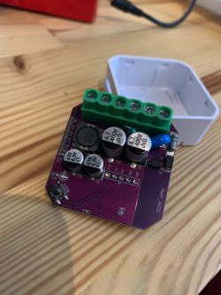 A blue circuit board with green terminals and capacitors on a wooden table.