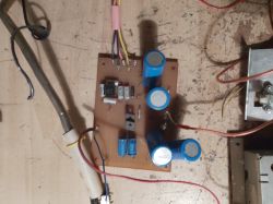 Płytka drukowana z niebieskimi kondensatorami elektrolitycznymi i elementami elektronicznymi.