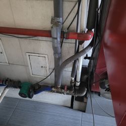 Instalacja grzewcza z rurami i zaworem w kotłowni.