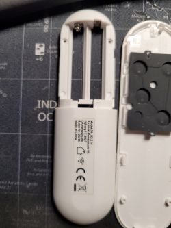 Disassembled remote control with batteries removed, showing interior and model label.